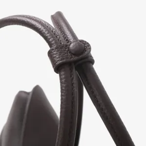 Détail de sac à épaule en cuir montrant une sangle de qualité et des boutons doux en cuir.