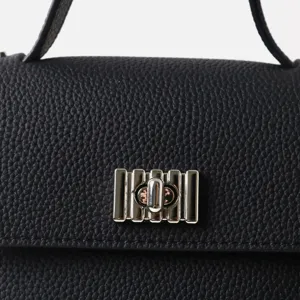 Détail de sac à main en cuir de vachette noir avec serrure en métal argenté élégante.