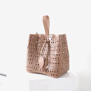 Vue rapprochée des détails élégants du sac seau en cuir découpé au laser couleur nude.