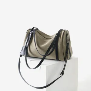 Détail du sac bandoulière en toile avec tissu texturé et lanières en cuir noir.