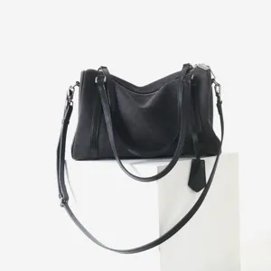 Détail de sac bandoulière minimaliste en toile noire, quincaillerie et lanière raffinées.