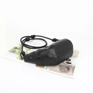 Sac bandoulière croissant en cuir véritable noir avec lanière nouée, style chic minimaliste.