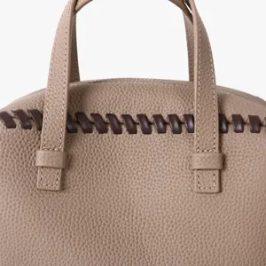Vue de détail d'un sac Boston en cuir taupe avec surpiqûre contrastée et doubles anses.