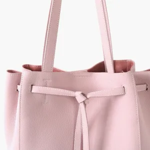 Gros plan sur le sac cabas en cuir rose avec détail de ceinture et belles finitions.