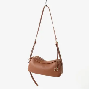 Gros plan sur le sac souple en cuir marron, mettant en valeur sa texture et ses boucles.