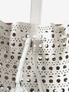 Sac seau en cuir blanc perfore au laser, design geometrique elegant avec cordon serrage.