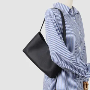 Vue détaillée du sac porté épaule minimaliste en cuir de vachette noir à la texture fine.