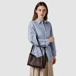 Vue détaillée du sac porté épaule hobo en cuir marron foncé porté par un mannequin en studio.