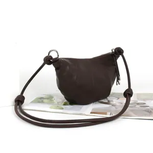Sac bandoulière croissant en cuir marron foncé minimaliste avec lanière nouée.