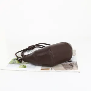 Vue détaillée du sac besace en cuir marron, texture souple avec lanière nouée et anneau.
