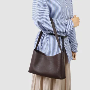 Gros plan détail d'un sac porté épaule hobo en cuir marron foncé sur mannequin de présentation.