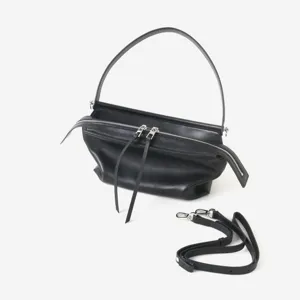 Détail du sac à main en cuir noir avec fermeture éclair en métal et bandoulière amovible.