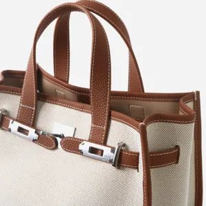 Gros plan sur le détail du sac fourre-tout en toile cuir, fermoir métallique, bordure marron.