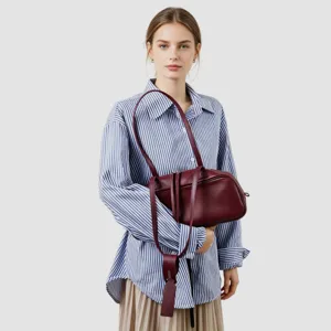 Bolso de hombro de cuero rojo oscuro llevado por modelo, gran capacidad elegante.