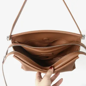 Vue détaillée de l'intérieur du sac à bandoulière en cuir marron avec compartiments et zips.