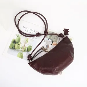Sac bandoulière croissant en cuir véritable bordeaux avec lanière nouée et design élégant.