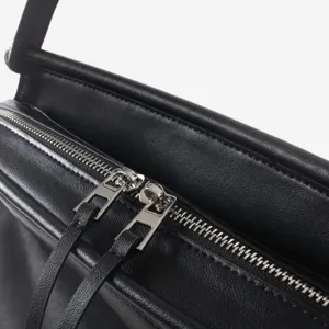 Gros plan detail sac a main en cuir noir avec fermeture eclair metallique pour travail.