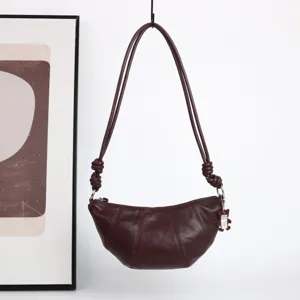 Gros plan d'un sac porté épaule croissant en cuir souple avec bandoulière nouée unique.