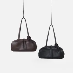 Vista detallada del bolso de hombro de cuero estilo bolos, diseño minimalista con cremallera.