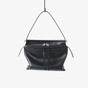 Détail de sac à bandoulière en cuir noir avec double fermeture éclair et lanière.