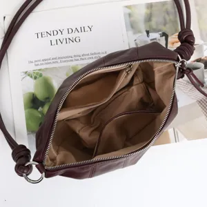 Vue détaillée de l'intérieur du sac souple en cuir, avec plusieurs compartiments et une fermeture.