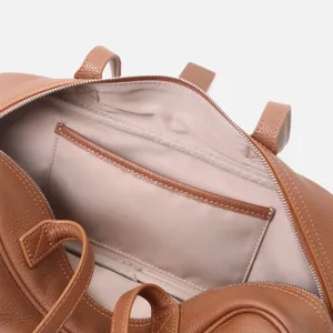 Detalle interior de bolso boston de cuero marrón con forro y bolsillo con cremallera, gran textura.