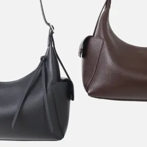 Detalle de bolso de hombro de cuero genuino con textura de vacuno y bolsillo lateral.