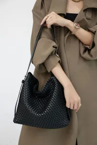 Détail rapproché du sac à épaule en cuir noir tressé avec un design élégant et raffiné.