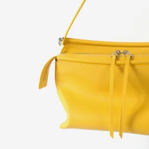 Détail de sac bandoulière en cuir jaune vif, design minimaliste moderne, texture douce.