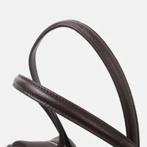 Detalle de asa de bolso de cuero de vaca marrón oscuro, textura premium y costuras.