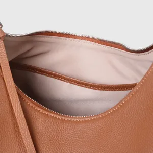 Detalle interior del bolso de cuero marron con cremallera suave y bolsillo util.