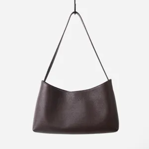 Détail de sac bandoulière hobo en cuir marron, design minimaliste, sac à main élégant.
