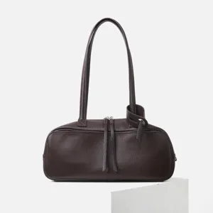 Bolso de hombro tipo bolos en cuero marrón oscuro, detalle de cremallera y asa con nudo.