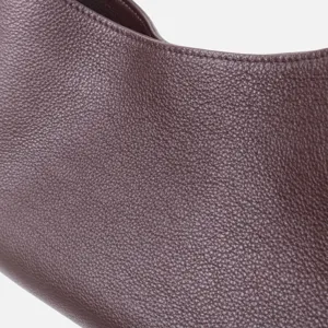Gros plan sur la texture du sac à main en cuir marron foncé et ses détails de coutures.
