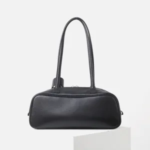 Vista detallada del bolso de bolos de cuero negro, elegante bolso boston con asas largas para uso.