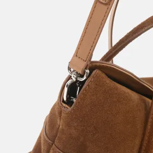 Gros plan des details de la bandouliere en cuir suede marron et connecteur en metal argente.