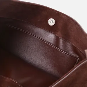 Détail intérieur de sac à main en cuir suédé marron avec poche et bouton pression de fermeture.