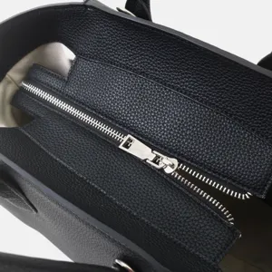 Vue détaillée d'un sac cabas en cuir noir véritable avec fermeture éclair argentée.