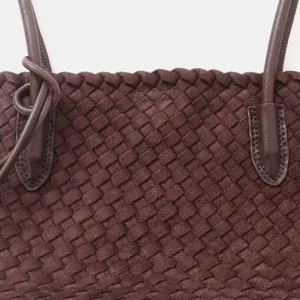 Gros plan détaillé de la poignée et de la texture tissée du sac cabas en cuir véritable.