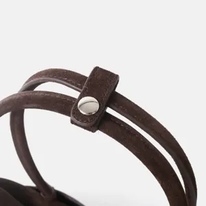 Détail de sac à main en daim marron, bandoulière en cuir chic avec bouton pression en métal.
