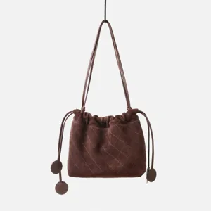 Gros plan sur le sac seau matelassé en suède marron, élégant cordon en cuir mat.