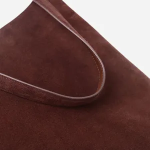 Gros plan detaille du bracelet de sac a main en daim marron avec une texture fine et couture.