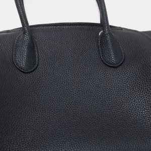 Vue rapprochée d'un sac cabas en cuir véritable noir avec détails de poignées texturées.