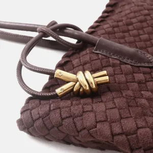 Détail de sac à main tressé en cuir marron avec texture intrecciato et nœud en métal doré.