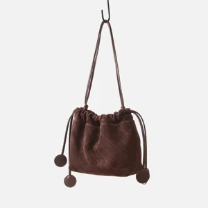 Détail de cordon matelassé en daim marron, sac à épaule texture douce affichage suspendu.