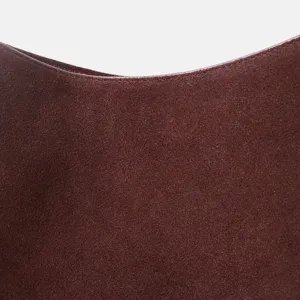 Détail de sac en daim marron montrant une texture douce et un bord incurvé élégant chic.