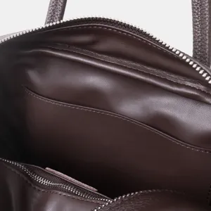 Gros plan détaillé de l'intérieur du sac à main pour femme en cuir marron avec fermeture.