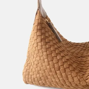 Gros plan détail d'un sac hobo en cuir tressé marron montrant la texture intrecciato.