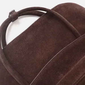 Détail de sac à main en cuir suédé marron montrant une texture fine et des coutures soignées.