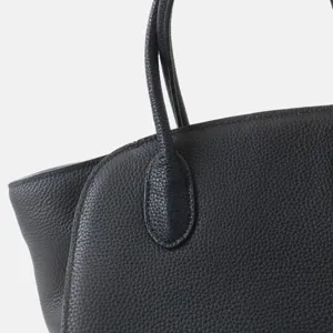Gros plan sur la poignée du sac fourre-tout noir, design texturé en cuir grainé de luxe.